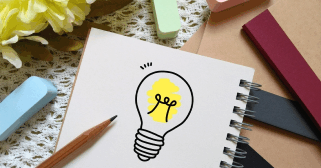 筆記用具と電球のイラストが描かれたノート